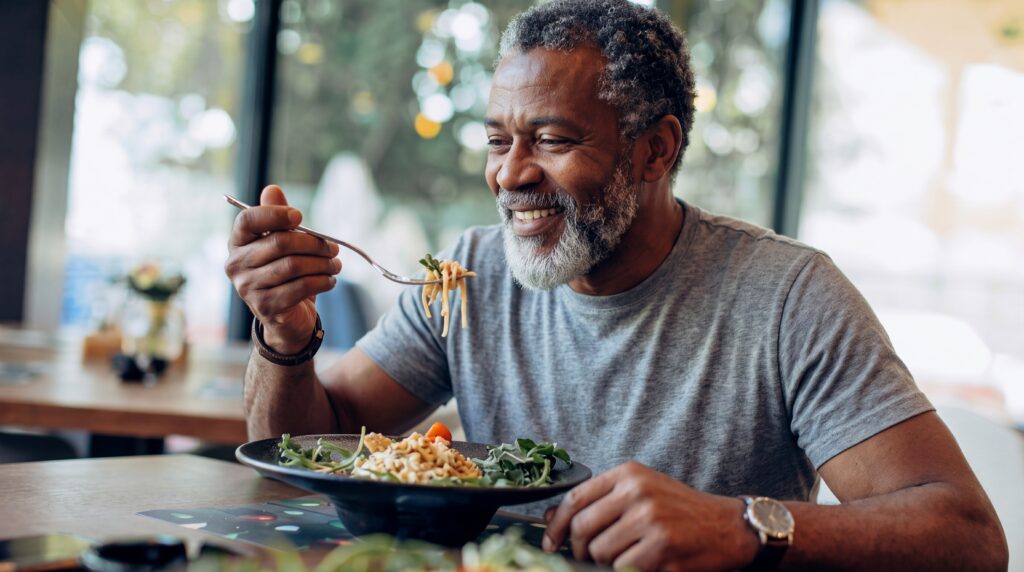 Older gentleman eats a protein dense dish with pasta and stack to support testosterone.